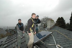 Photo of City Councilmember Mike O'Brien helping install a solar panel.