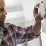 Photo of man setting his thermostat.