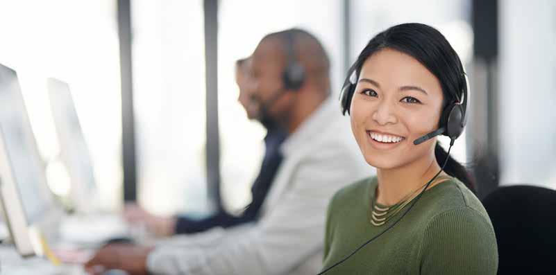 A woman in a call center smiles at the camera
