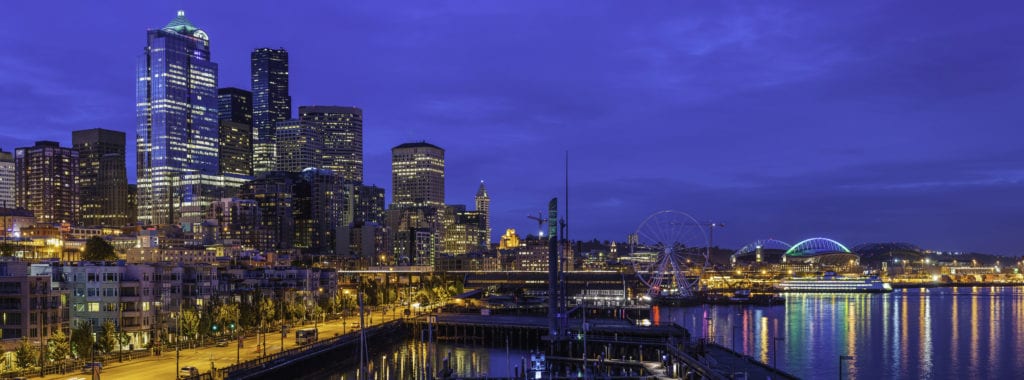 Decorative photos of a panoramic vista over the night lights and crowded cityscape of the Seattle waterfront, from the marina and luxury condominiums past the soaring skyscrapers of downtown to the aquarium and ferry docks on Puget Sound, Washington, USA. 