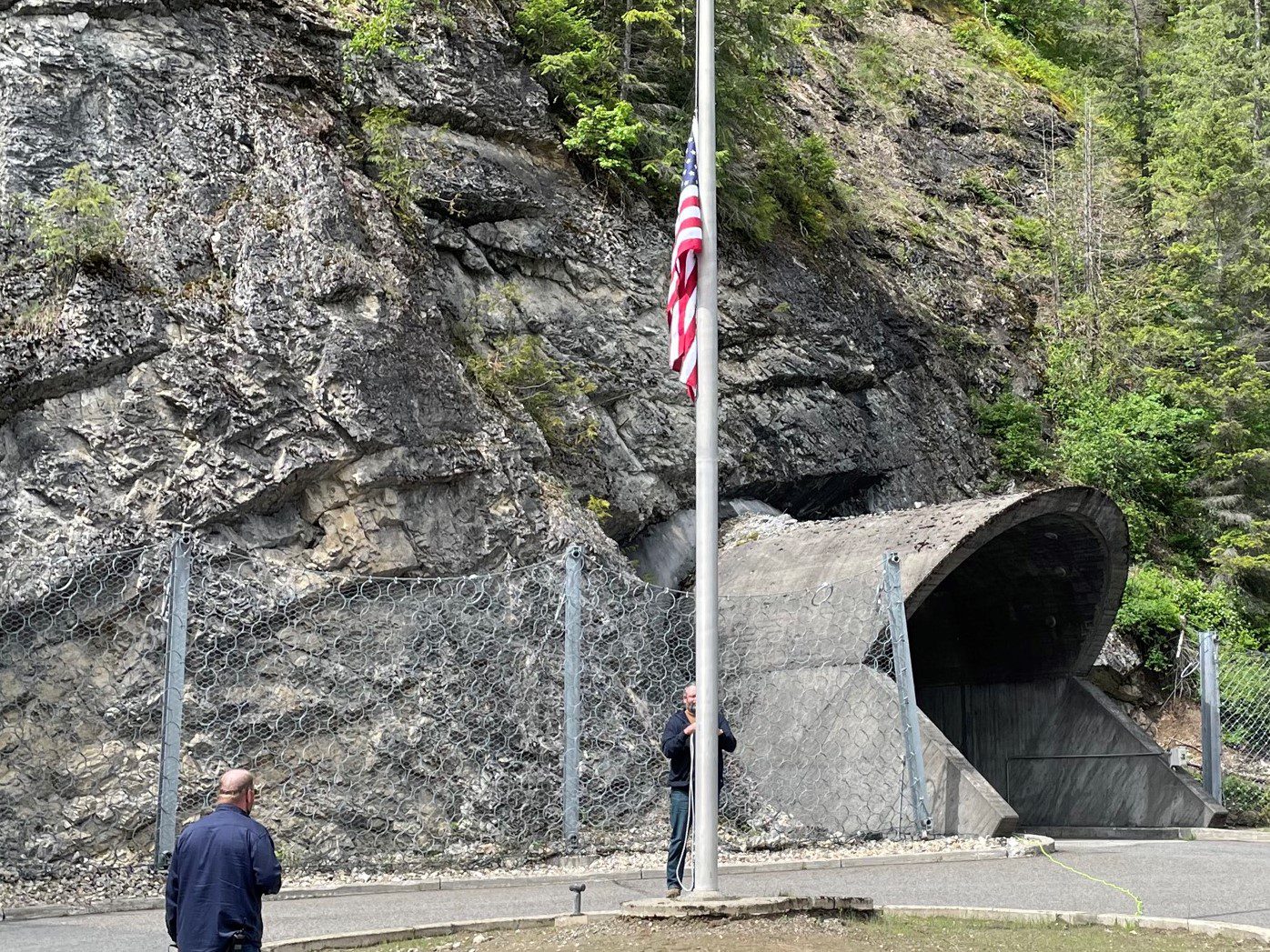 Seattle City Light workers at Boundary Hydroelectric Project salute the American flag, lowered to half mast.