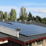 Solar panel installation on roof with trees in background.